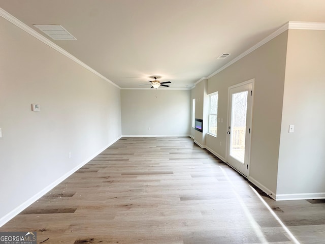 spare room with light wood-style floors, baseboards, visible vents, and ornamental molding