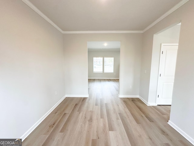 spare room featuring light wood-type flooring, crown molding, and baseboards