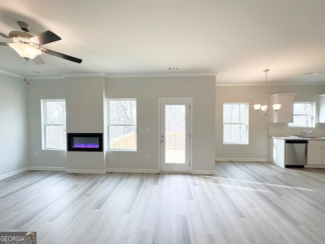 unfurnished living room featuring light wood-style floors, visible vents, plenty of natural light, and a sink