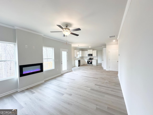 unfurnished living room featuring ceiling fan, baseboards, light wood finished floors, a glass covered fireplace, and crown molding