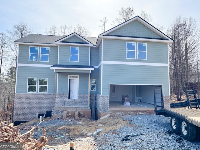 view of front of property featuring a garage, brick siding, driveway, and a patio