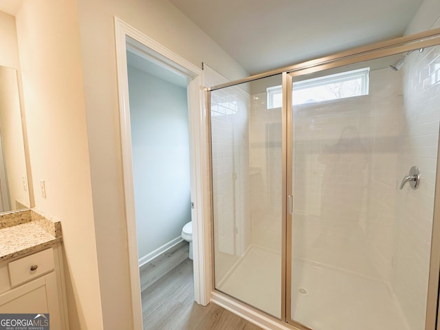 full bath with wood finished floors, a stall shower, vanity, and toilet