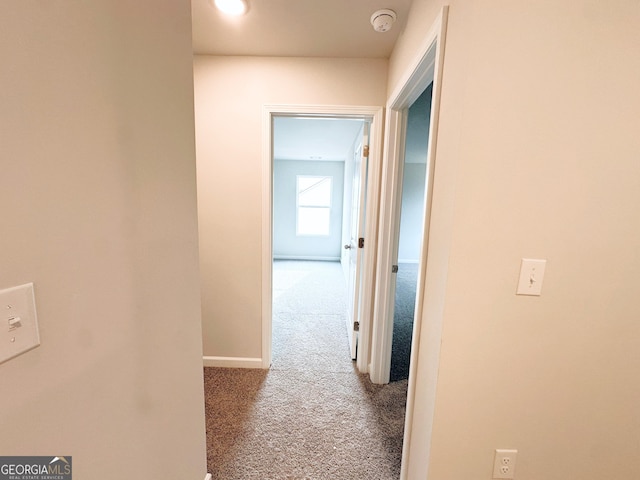 hall featuring carpet and baseboards