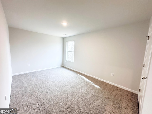 spare room with baseboards and carpet flooring