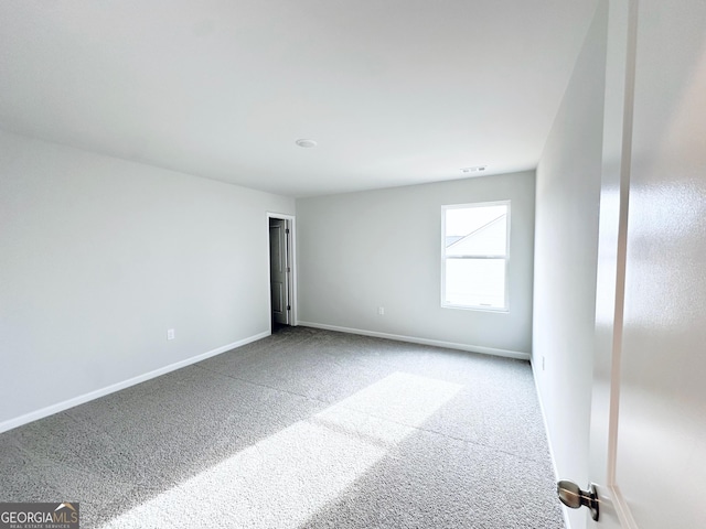 empty room featuring carpet floors, visible vents, and baseboards