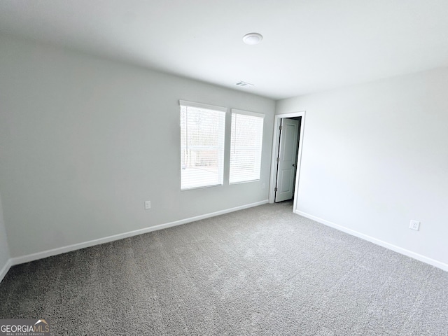 empty room featuring carpet, visible vents, and baseboards