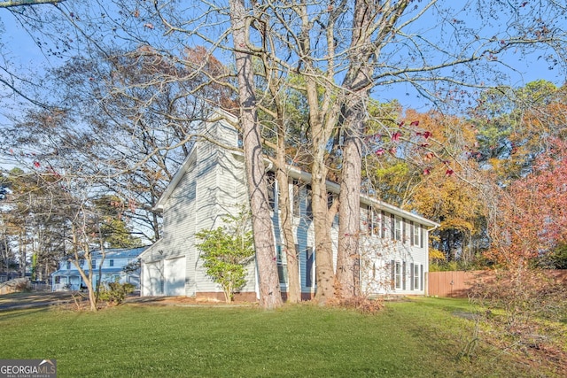 view of side of home featuring a garage, a yard, and fence