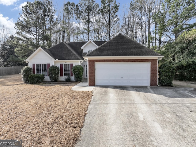 ranch-style home with an attached garage, fence, concrete driveway, and brick siding