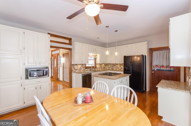 kitchen featuring light wood-style flooring, white cabinetry, appliances with stainless steel finishes, backsplash, and a center island