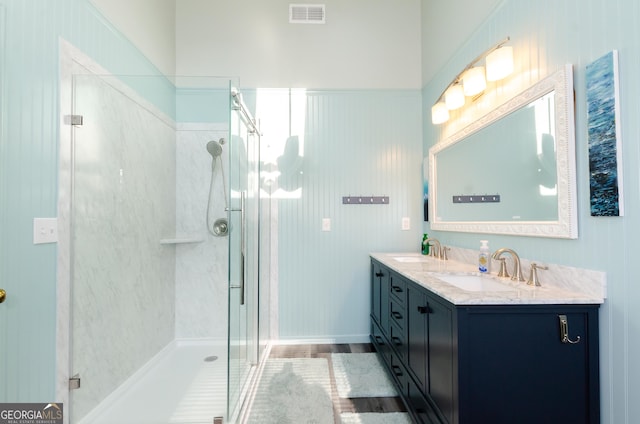 bathroom featuring double vanity, a stall shower, visible vents, and a sink