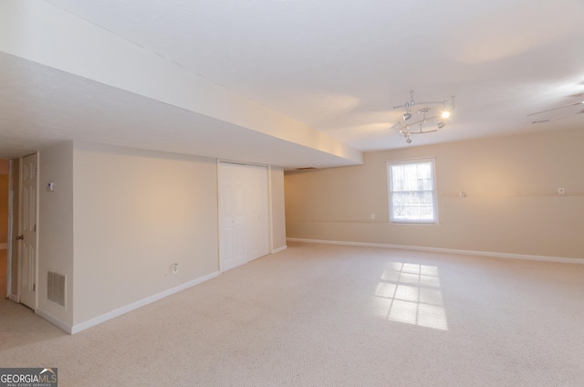 basement featuring light carpet, baseboards, and visible vents