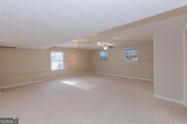 carpeted empty room with ceiling fan, a textured ceiling, and baseboards