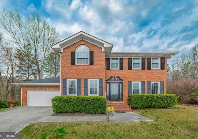 colonial inspired home with a garage, brick siding, a front yard, and aphalt driveway