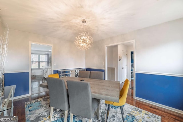 dining room featuring baseboards, wood finished floors, visible vents, and a notable chandelier