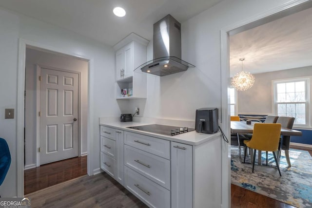 kitchen featuring black electric stovetop, light countertops, dark wood-type flooring, white cabinets, and wall chimney exhaust hood