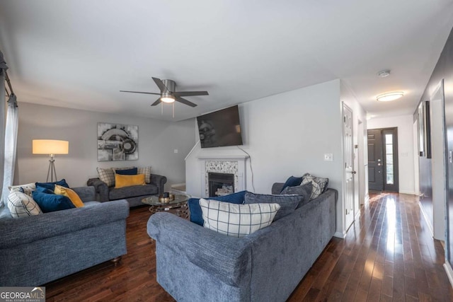 living area with a tile fireplace, dark wood finished floors, a ceiling fan, and baseboards