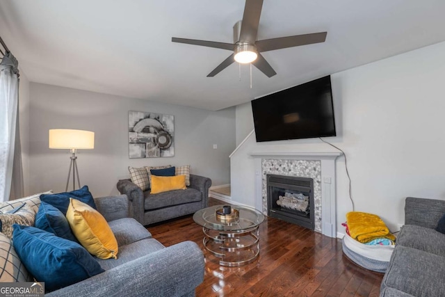 living area with a tiled fireplace, ceiling fan, and wood-type flooring