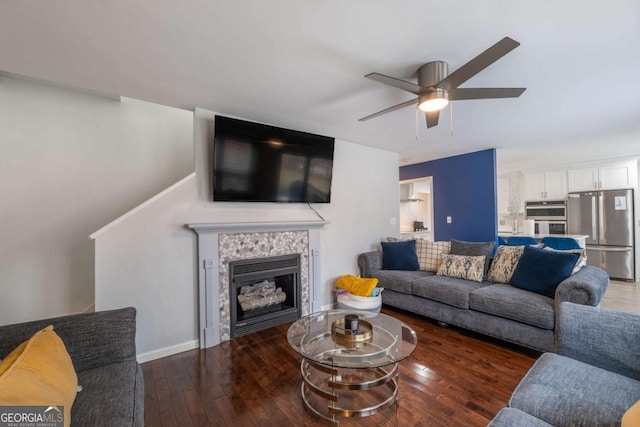 living area with a ceiling fan, wood-type flooring, a fireplace, and baseboards