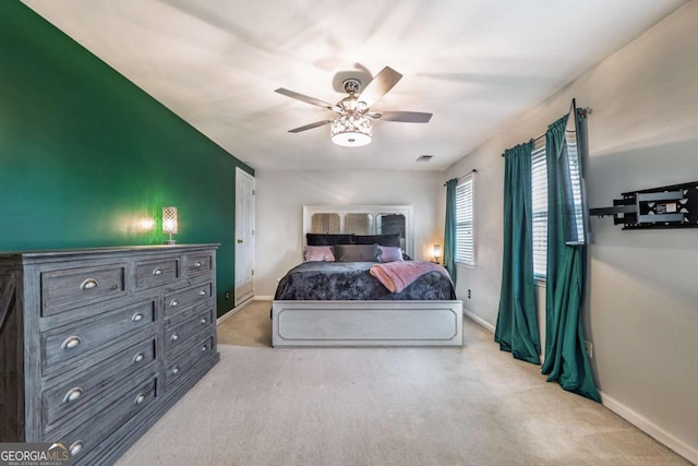 carpeted bedroom featuring a ceiling fan, visible vents, and baseboards