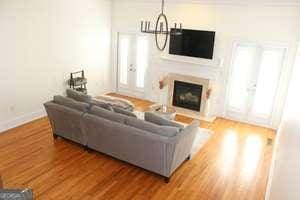 living room with a glass covered fireplace, baseboards, an inviting chandelier, and wood finished floors