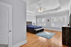 bedroom with wood finished floors, a raised ceiling, and baseboards