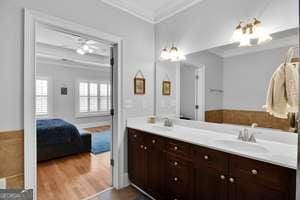 bathroom with double vanity, ornamental molding, a sink, and wood finished floors