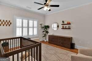 bedroom with baseboards, wood finished floors, a ceiling fan, and crown molding