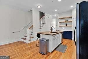 kitchen featuring light wood-style flooring, a center island with sink, a sink, and freestanding refrigerator