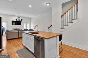 kitchen featuring a center island with sink, recessed lighting, light wood-style flooring, a sink, and dishwasher