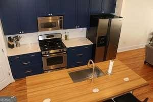 kitchen featuring appliances with stainless steel finishes, wood finished floors, light countertops, blue cabinetry, and a sink