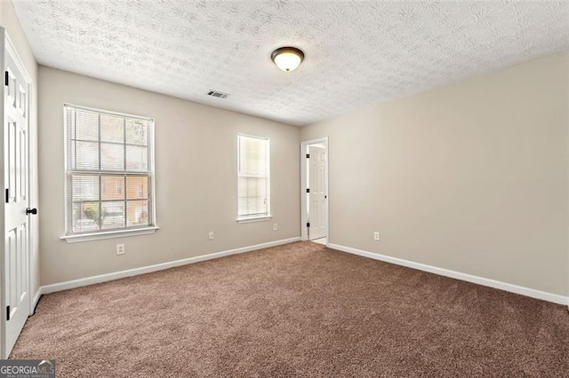 unfurnished room featuring carpet, a textured ceiling, visible vents, and baseboards