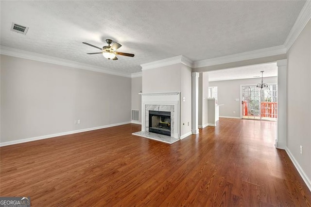 unfurnished living room featuring dark wood-type flooring, visible vents, a fireplace, and ceiling fan with notable chandelier