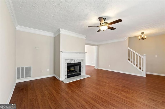 unfurnished living room featuring wood finished floors, a high end fireplace, visible vents, ornamental molding, and stairway