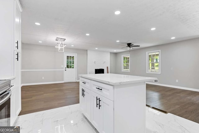 kitchen featuring white cabinets, marble finish floor, open floor plan, and recessed lighting