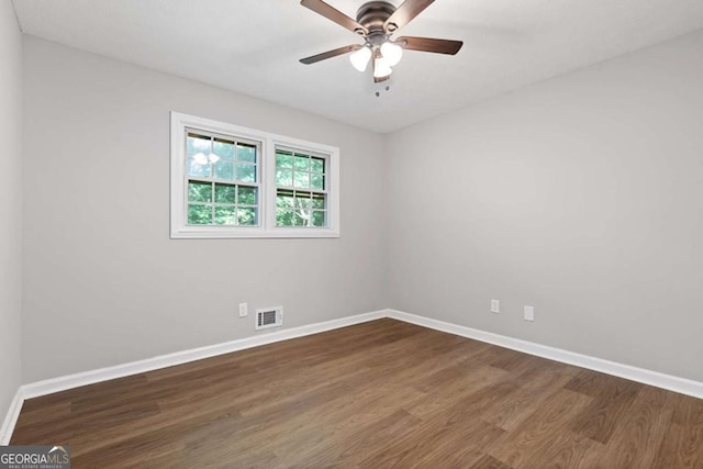 empty room featuring wood finished floors, visible vents, and baseboards