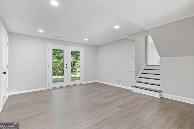 unfurnished living room with visible vents, stairway, wood finished floors, and french doors