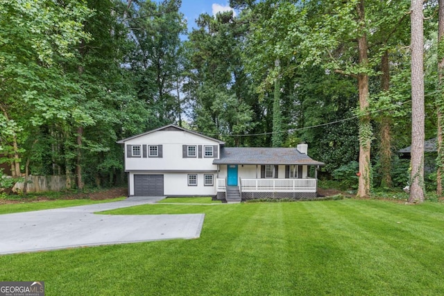 split level home with a garage, concrete driveway, covered porch, a front yard, and stucco siding