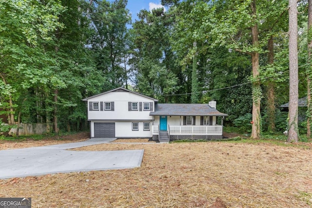 split level home featuring covered porch, concrete driveway, an attached garage, and stucco siding