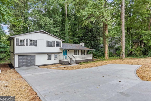 tri-level home with a porch, driveway, and a chimney