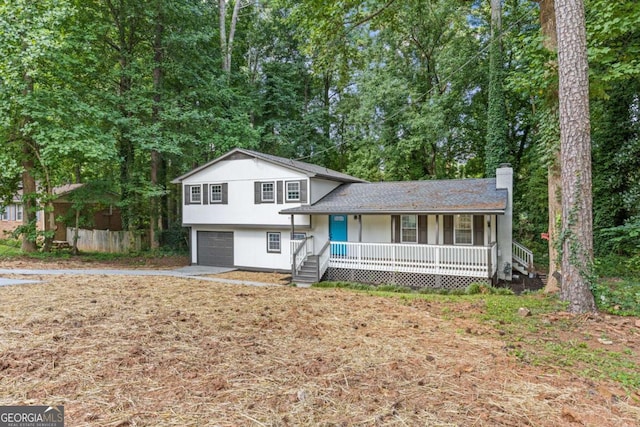 tri-level home with covered porch, a chimney, an attached garage, and concrete driveway