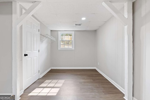 interior space featuring a drop ceiling, wood finished floors, visible vents, and baseboards