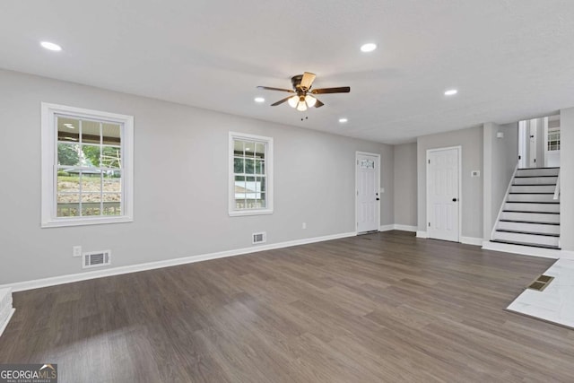 unfurnished living room with stairs, wood finished floors, visible vents, and baseboards