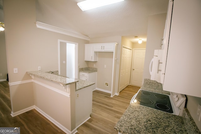 kitchen featuring light stone counters, white cabinets, wood finished floors, range with electric cooktop, and a peninsula