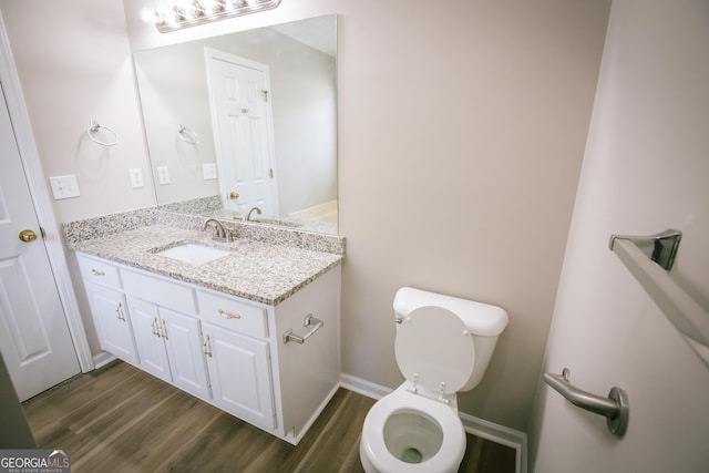 half bath with vanity, toilet, and wood finished floors