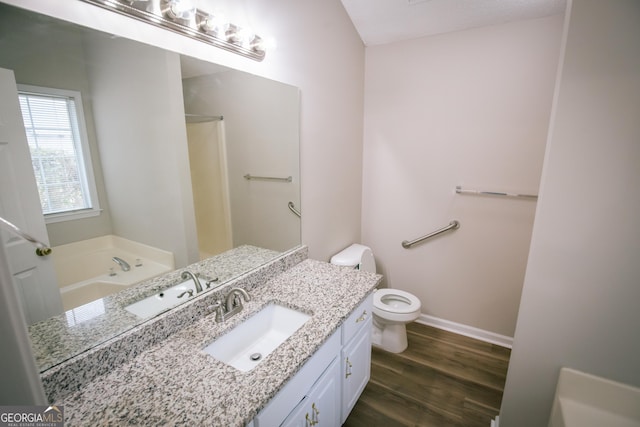 bathroom with a washtub, toilet, wood finished floors, vanity, and baseboards