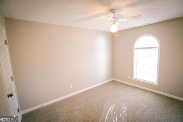 empty room with visible vents, baseboards, a ceiling fan, carpet, and a textured ceiling