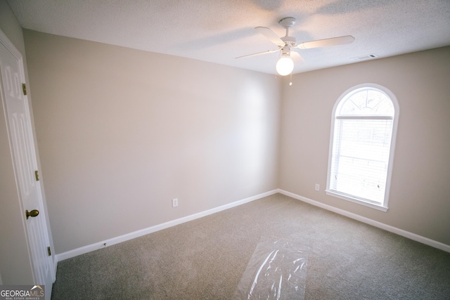 empty room with baseboards, visible vents, a textured ceiling, and carpet flooring