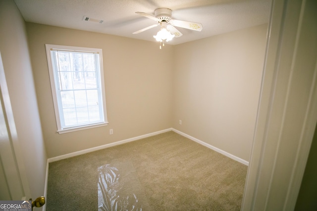 empty room featuring ceiling fan, carpet flooring, visible vents, and baseboards