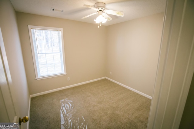 carpeted empty room featuring a ceiling fan, visible vents, and baseboards