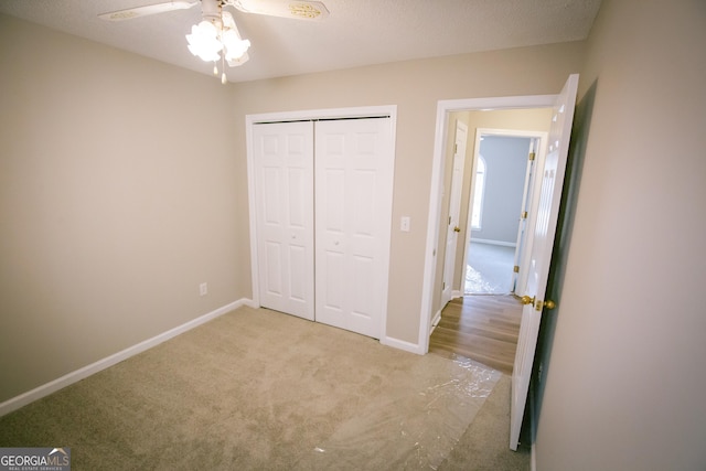 unfurnished bedroom with a closet, carpet flooring, a ceiling fan, and baseboards